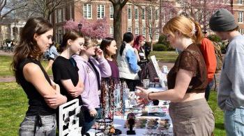 A group of students looking at jewelry and other crafts at a table at a pop-up event on Polk Place on the campus of UNC-Chapel Hill.